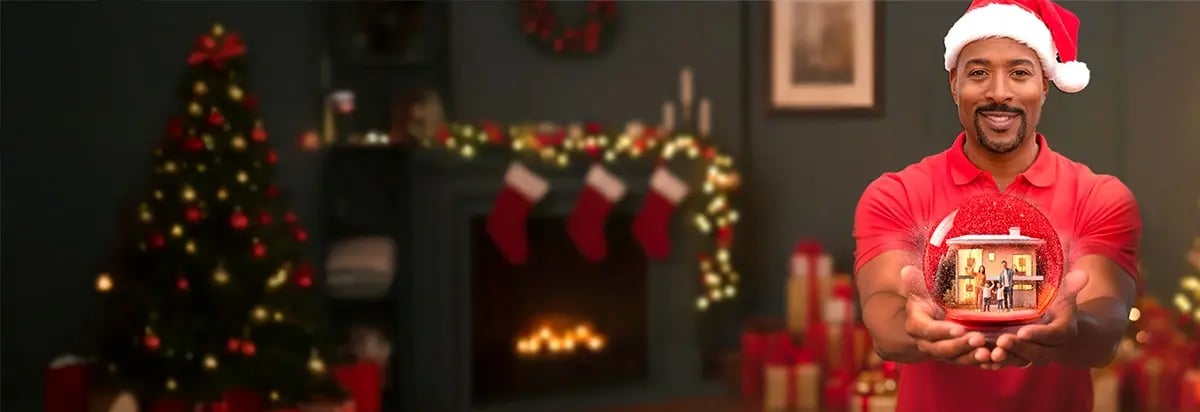 Homme tenant une maison protégée par une alarme et un service de télésurveillance