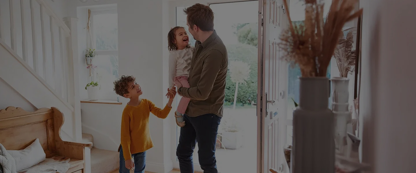 Famille souriante devant la porte d’entrée d’une maison moderne, moment de convivialité