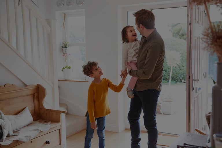 Famille souriante devant la porte d’entrée d’une maison moderne, moment de convivialité