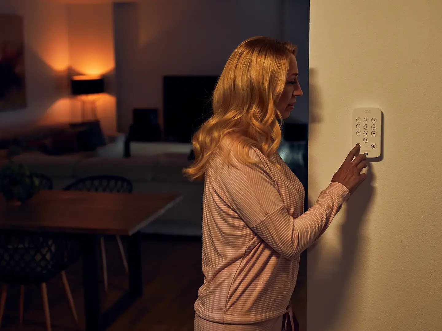 femme activant son alarme maison Sector Alarm via le clavier mural femme activant son alarme maison Sector Alarm via le clavier mural